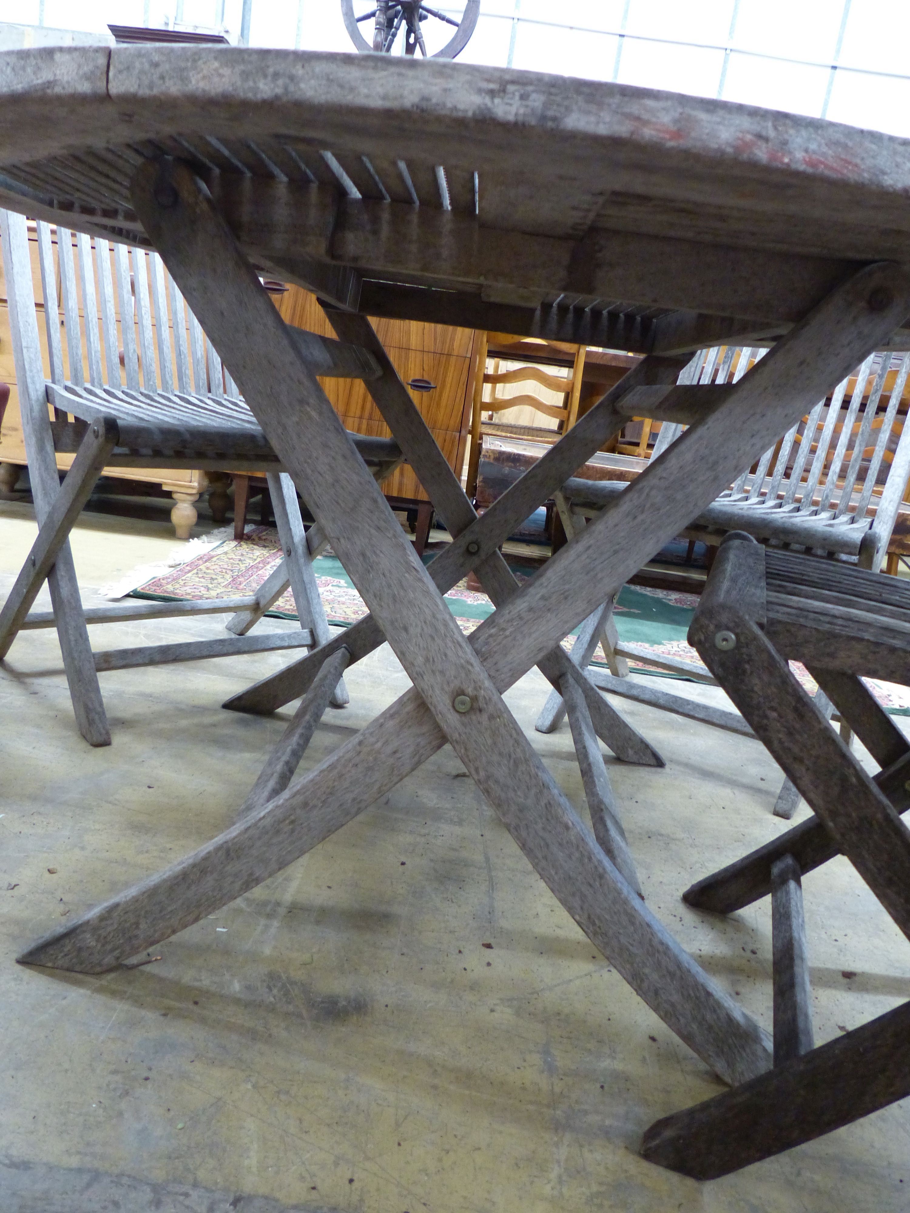 A teak garden table, 125cm diameter and four matching chairs, all folding